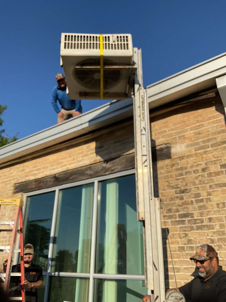 Cool Bear team lifting and installing a new HVAC unit