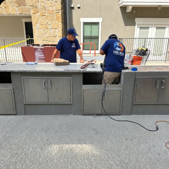 Cool Bear technicians working on an outdoor grill counter at an apartment community in San Marcos, Texas