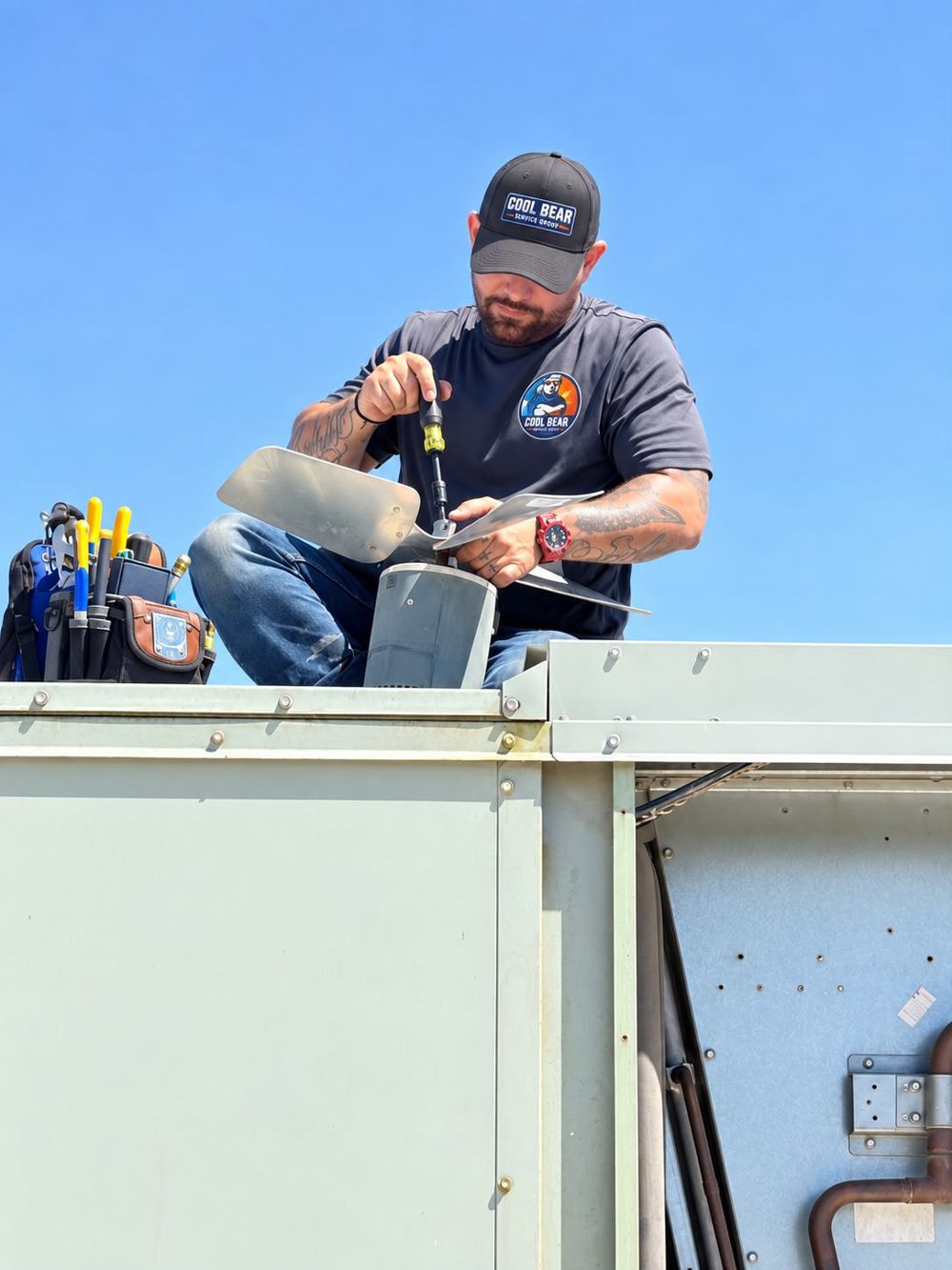 Cool Bear Service Group technician replacing a fan blade on a commercial rooftop HVAC unit