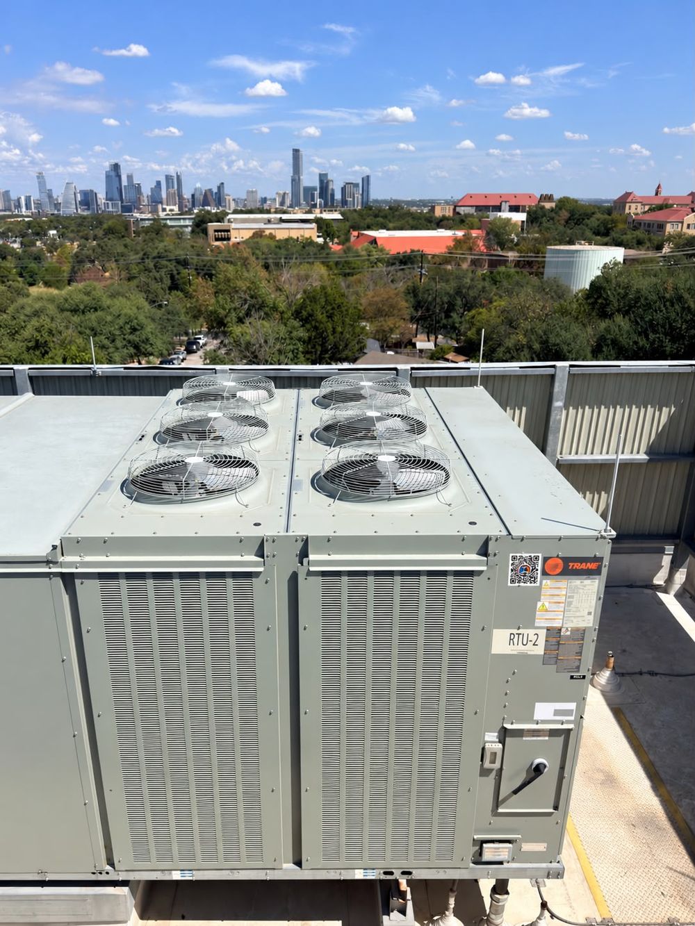 Trane rooftop unit RTU-2 with six condenser fans and the Austin skyline in the background